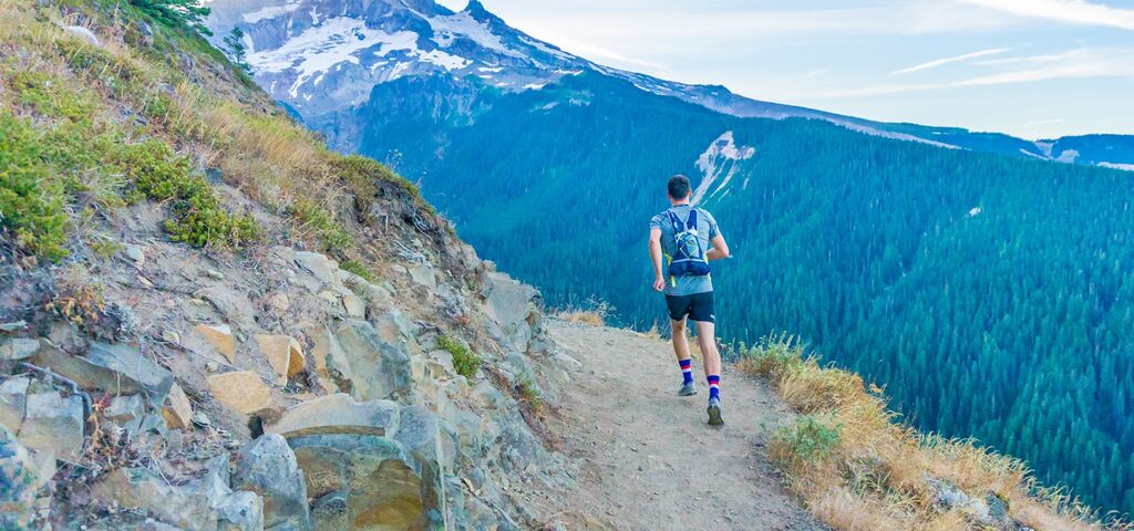Trailer courant sur un sentier de montagne avec vue panoramique sur les sommets enneigés